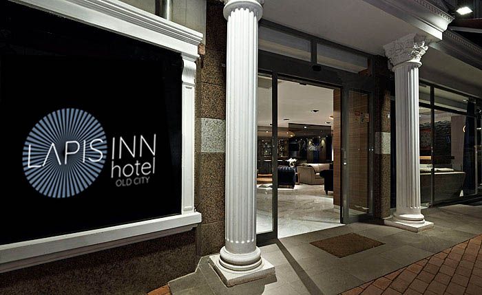 The entrance of Lapis Inn at night, the sign lit above the door