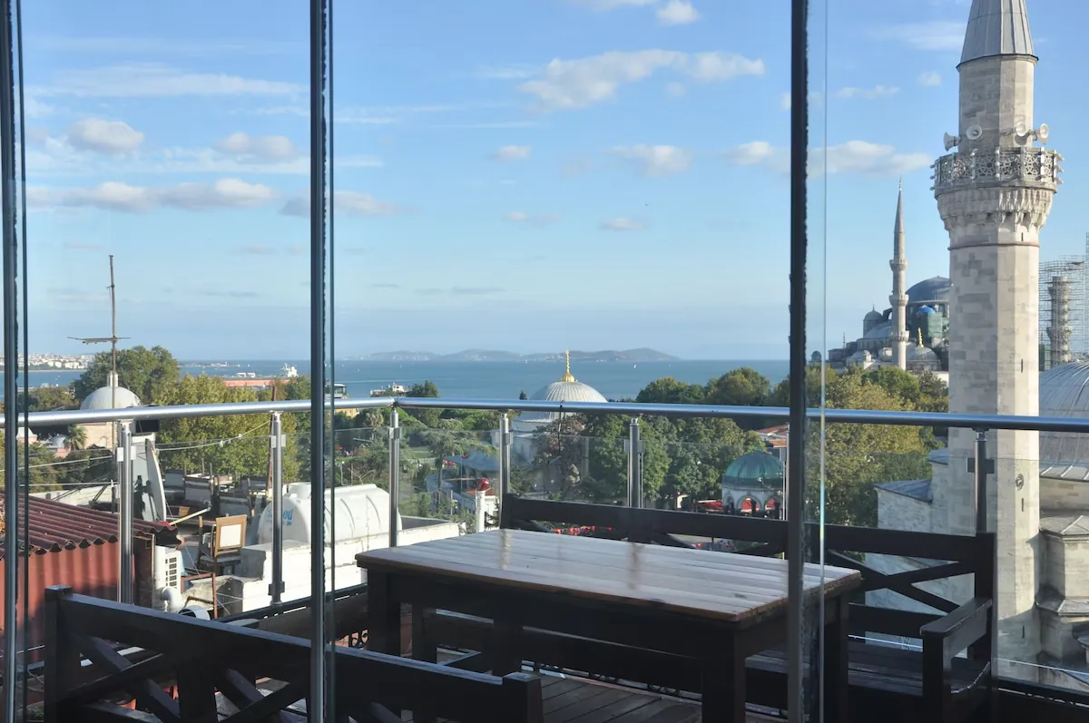 The glassed rooftop terrace with a sea and minaret view through the windows