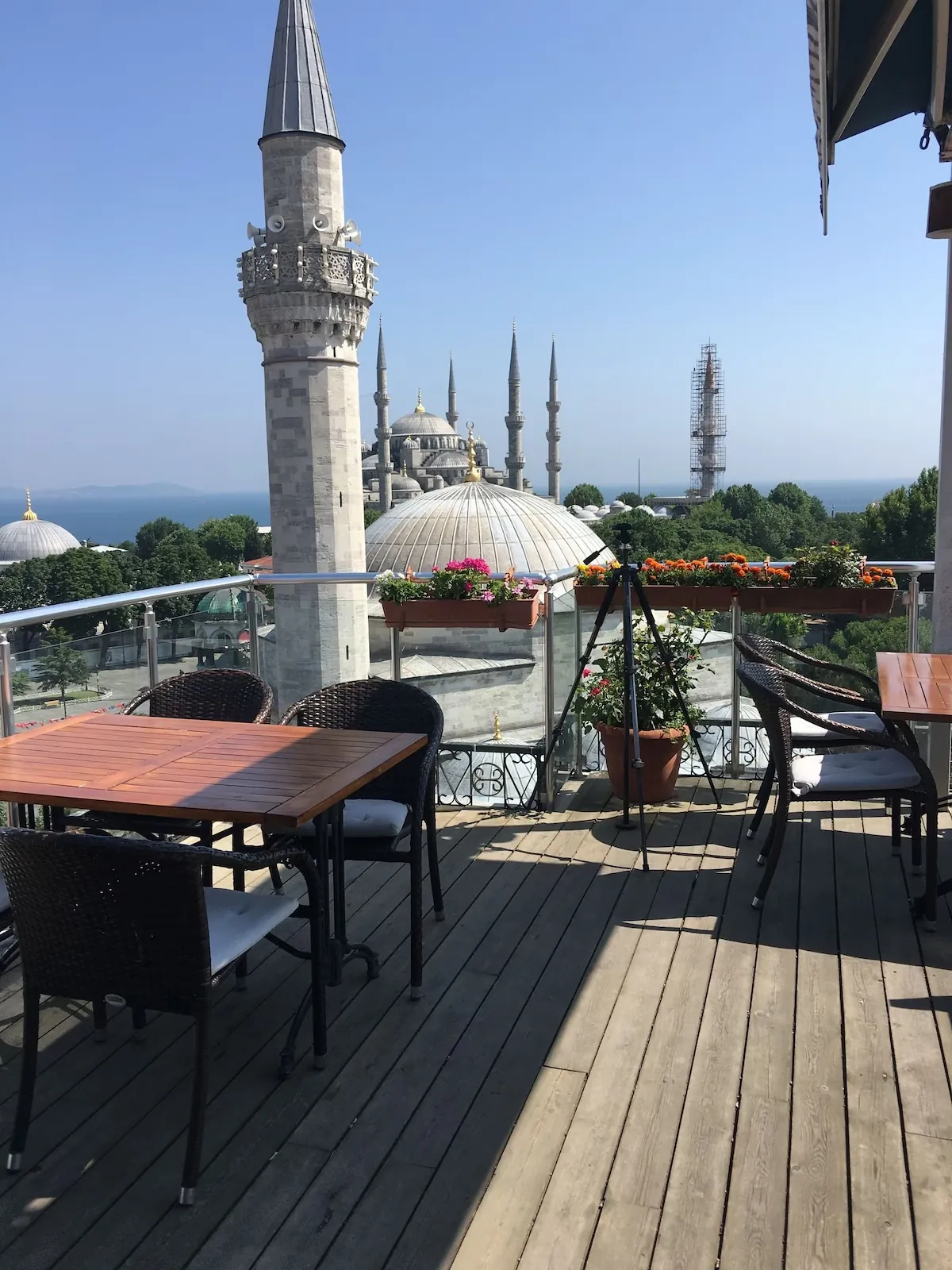 Open-air terrace deck with tables, planters and the Blue Mosque minarets beyond