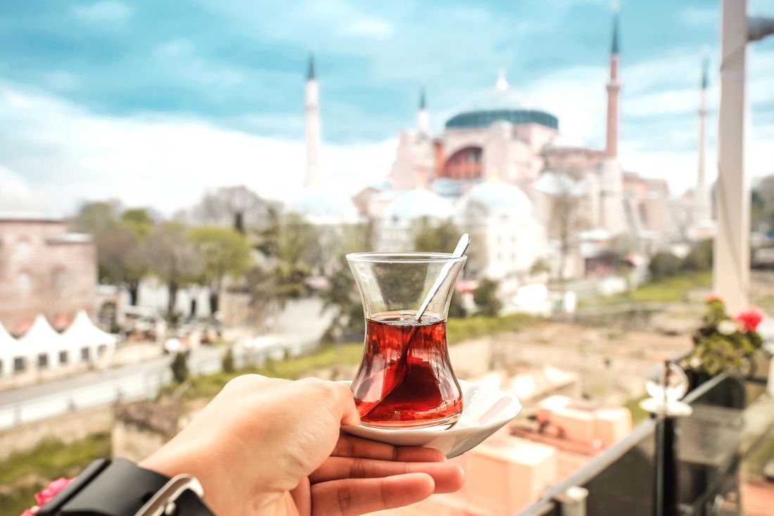 A glass of Turkish tea held up against the domes of the old city